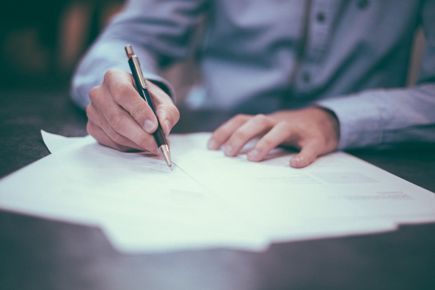 Hands signing a document at a desk, standing in for review and sign-off inside a tax application.